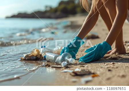 Woman wearing gloves picks up litter on a beach 118097651