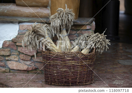 Rustic decor. In a wicker basket, ears of wheat are twisted into bouquets. 118097718