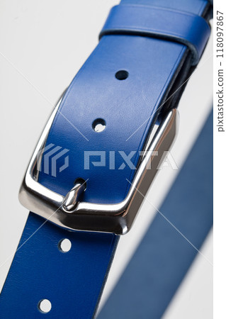 Part of a blue leather classic belt with a buckle on a gray background. Part of a blue leather classic belt with a buckle on a gray background. 118097867