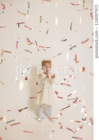 Happy little girl catches flying shiny confetti. 118097915