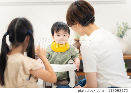 An older sister feeding her 0-year-old brother baby food 118098373