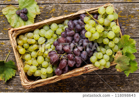A wicker basket brimming with a variety of grapes A wicker basket brimming with a variety of grapes 118098643