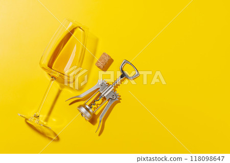 Wine glass alongside a corkscrew and several corks 118098647