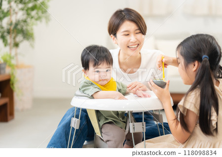 An older sister feeding her 0-year-old brother baby food 118098834