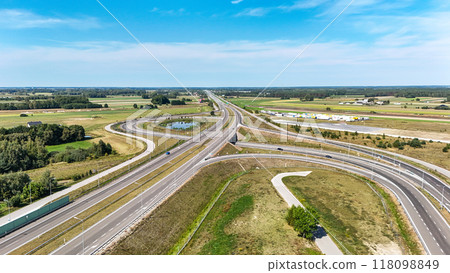 Aerial photograph of a highway intersection with natural, subdued colors. The scene highlights the blend of infrastructure and nature, with roads weaving through a tranquil suburban landscape. Aerial photograph of a highway intersection with natural, subdued colors. The scene highlights the blend of infrastructure and nature, with roads weaving through a tranquil suburban landscape. 118098849