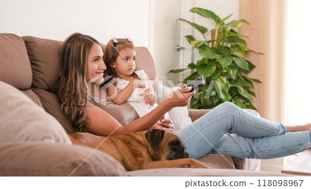 Happy family with cute dog watching TV on couch at home Happy family with cute dog watching TV on couch at home 118098967