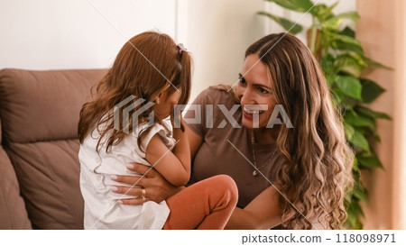 Cheerful woman and daughter playing peek a boo at home 118098971