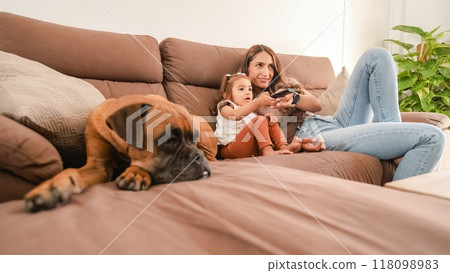 Happy mother and girl watching TV beside dog at home 118098983