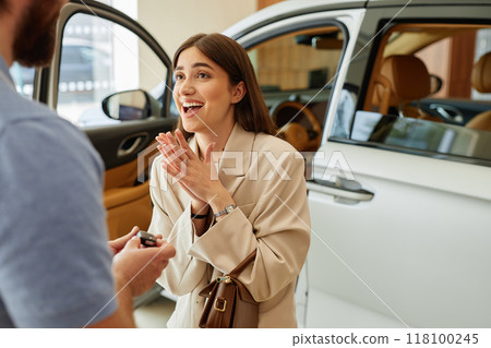 Medium shot of surprised happy woman receiving car key as present from boyfriend at dealership center. Dreams come true, copy space Medium shot of surprised happy woman receiving car key as present from boyfriend at dealership center. Dreams come true, copy space 118100245