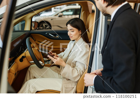 Young fashionable woman at drivers seat reading about car performance using digital tablet while testing demo vehicle at dealership center Young fashionable woman at drivers seat reading about car performance using digital tablet while testing demo vehicle at dealership center 118100251