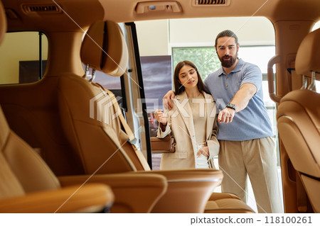 Shot from car cabin with beige leather interior of adult woman and man deciding on buying new car ,discussing passenger compartment design of demo model displayed at dealership center 118100261