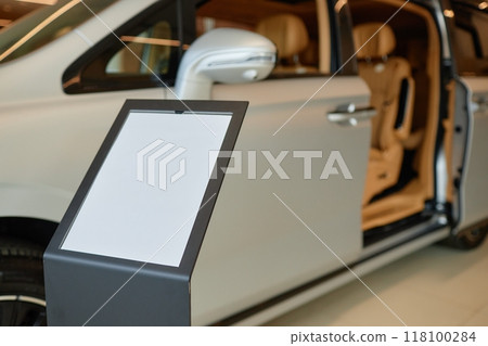Car dealership information stand with blank mockup sheet displaying vehicle specifications in showroom, copy space 118100284