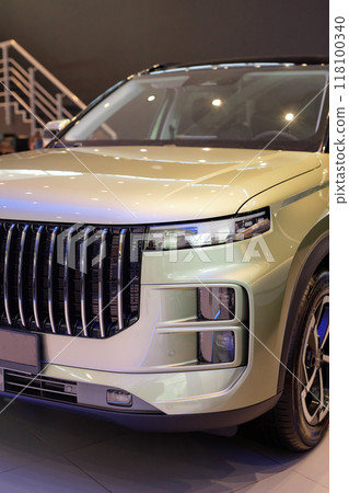 Vertical shot of SUV automobile with xenon headlights. Modern looking demo vehicle with brutal design displayed in car showroom at dealership center Vertical shot of SUV automobile with xenon headlights. Modern looking demo vehicle with brutal design displayed in car showroom at dealership center 118100340