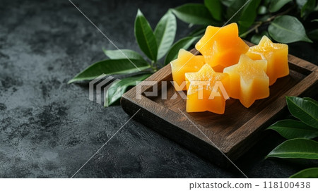 Mango jelly squares on a white plate against a rustic wooden background. Simple and refreshing tropical dessert perfect for summer recipes and light treats. Mango jelly squares on a white plate against a rustic wooden background. Simple and refreshing tropical dessert perfect for summer recipes and light treats. 118100438