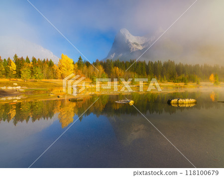 Nature. Autumn trees on the lake shore. Fall landscape with fog. Mountains and forest. Nature. Autumn trees on the lake shore. Fall landscape with fog. Mountains and forest. 118100679