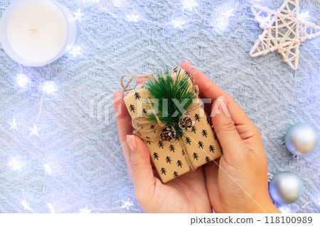 Woman's hands hold a small christmas gift Woman's hands hold a small christmas gift 118100989
