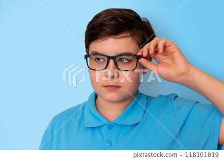 Close up of cute schoolboy in glasses on blue background 118101019