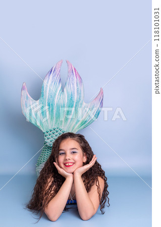 A pretty girl in a mermaid costume lie on light-blue background A pretty girl in a mermaid costume lie on light-blue background 118101031