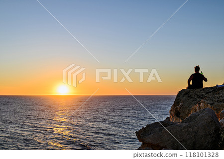 Young man watching the sunset on the Barbate beach next to the Trafalgar lighthouse, Cadiz 118101328