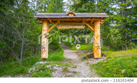 A wooden archway marks the entrance to the symbolic cemetery honoring the victims of the Low Tatras, nestled in the serene Demanovska Valley, Slovakia, surrounded by lush greenery. A wooden archway marks the entrance to the symbolic cemetery honoring the victims of the Low Tatras, nestled in the serene Demanovska Valley, Slovakia, surrounded by lush greenery. 118101404