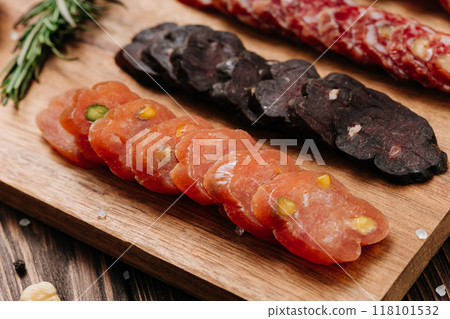 Sliced sausage with pistachios on wooden board, ideal for food presentations and gourmet displays 118101532