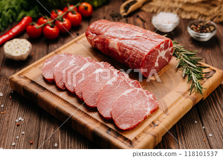 Raw pork loin with rosemary and fresh tomatoes on cutting board, perfect for culinary presentations Raw pork loin with rosemary and fresh tomatoes on cutting board, perfect for culinary presentations 118101537