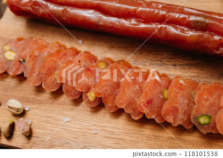 Sliced sausage with pistachios on wooden board, ideal for food presentations and gourmet displays 118101538
