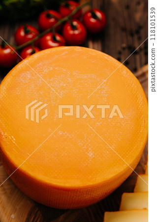 Golden cheese wheel and slice on wooden board, ideal for food photography and culinary presentations Golden cheese wheel and slice on wooden board, ideal for food photography and culinary presentations 118101539