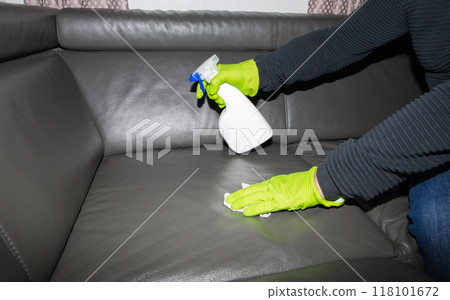 A man wearing cleaning gloves wipes the leather sofa. A man wearing cleaning gloves wipes the leather sofa. 118101672