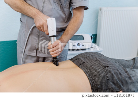 Shockwave therapy session for back pain relief in a clinical setting with a professional therapist Shockwave therapy session for back pain relief in a clinical setting with a professional therapist 118101975