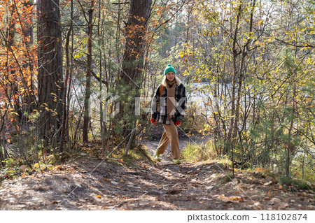 Woman walking in autumn forest in Scandinavia near pond. Female enjoying pastime hiking in park. Woman walking in autumn forest in Scandinavia near pond. Female enjoying pastime hiking in park. 118102874