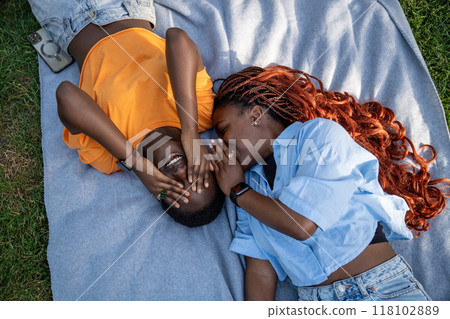 Happy african american girls friends lying on park grass gossips, laugh with eyes covers with palms. Happy african american girls friends lying on park grass gossips, laugh with eyes covers with palms. 118102889