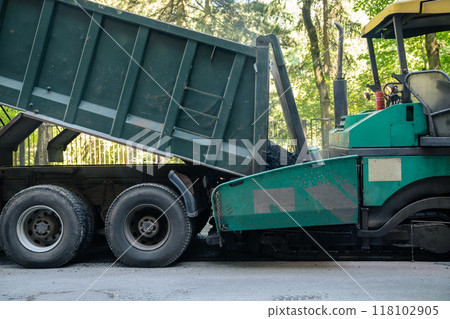 Construction vehicle is pouring asphalt. Road repair, fresh asphalt before paving 118102905