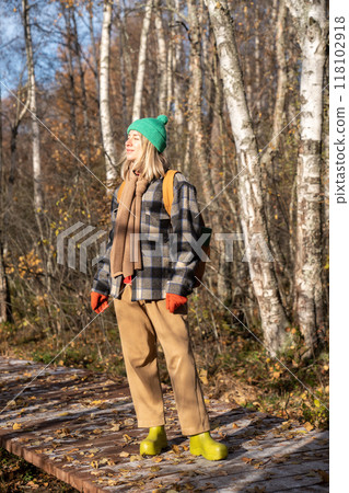Happy relaxed woman basks in sunlight on eco trail walk in autumn forest. Domestic tourism in nature 118102918