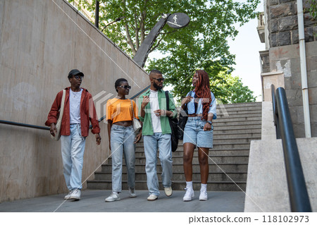Group of thoughtful African American friends enthusiastically discuss various topics, walk outdoors 118102973