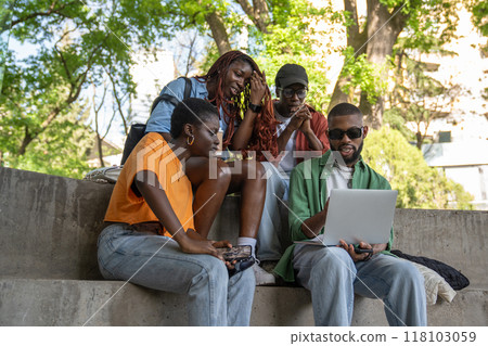 Happy black friends relaxing outside, watching interesting videos, lectures on laptop together Happy black friends relaxing outside, watching interesting videos, lectures on laptop together 118103059