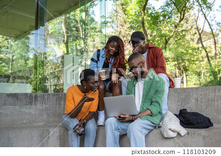 Friendly company of black students with laptop study in park, watch videos, discuss difficult topics 118103209