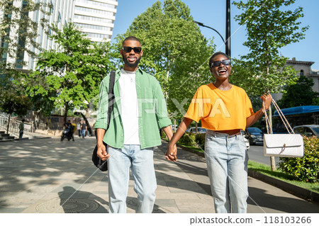 Happy lovers couple of African American students walking together, holding hands, laughing merrily. Happy lovers couple of African American students walking together, holding hands, laughing merrily. 118103266