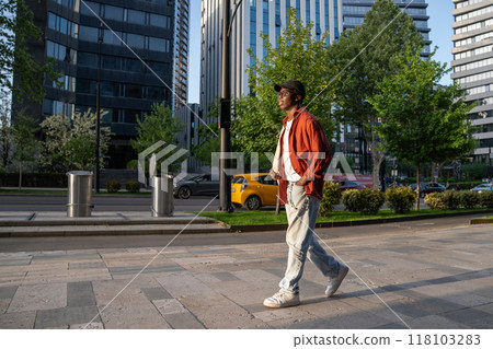 Relaxed African American guy on peaceful quite stroll around town, man walking through city street Relaxed African American guy on peaceful quite stroll around town, man walking through city street 118103283