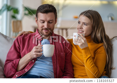 Happy and calm spouses drinking coffee or tea and hugging, sitting on sofa. Role model of family Happy and calm spouses drinking coffee or tea and hugging, sitting on sofa. Role model of family 118103327