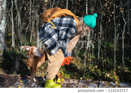 Playful female backpacker bonding, fooling around with dog in autumn park. Play with pet in nature Playful female backpacker bonding, fooling around with dog in autumn park. Play with pet in nature 118103357