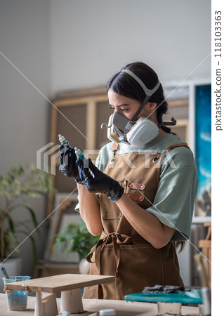 Artisan woman in respirator, gloves chooses pigment for creating specific color tones, paints, craft 118103363