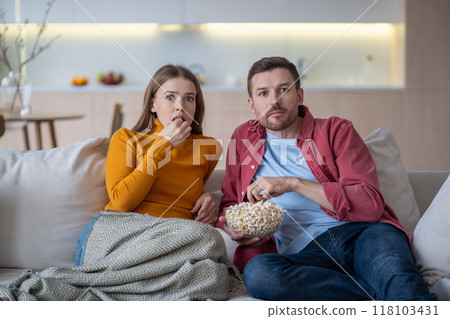 Surprised couple amazed by sudden turn of events in film, show, program while watching TV at home 118103431