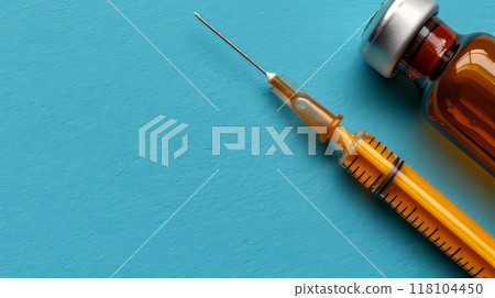 Top view of vaccine bottle and syringe on blue background with ample space for text placement 118104450