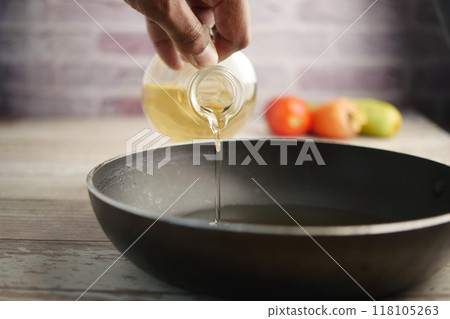 Pouring Oil into a Bowl A Detailed Cooking Preparation Scene in the Atmosphere of a Kitchen Pouring Oil into a Bowl A Detailed Cooking Preparation Scene in the Atmosphere of a Kitchen 118105263