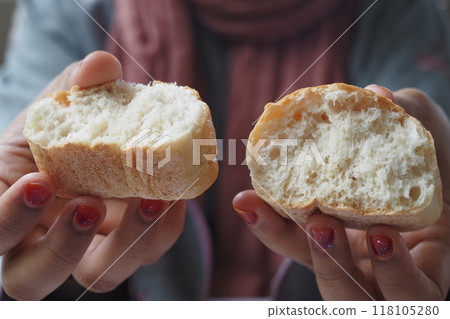 Hands are busy breaking fresh bread with wholesome ingredients beautifully arranged on a table 118105280