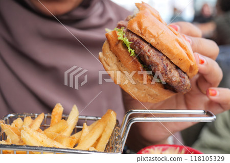 woman hand holding a beef burger enjoying her meal woman hand holding a beef burger enjoying her meal 118105329