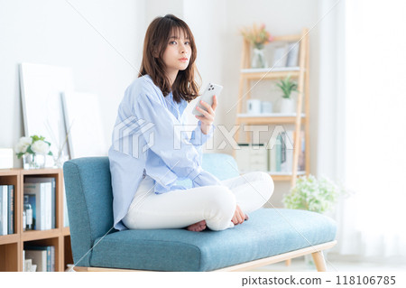 Young woman sitting and relaxing in living room 118106785