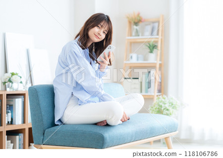 Young woman sitting and relaxing in living room Young woman sitting and relaxing in living room 118106786