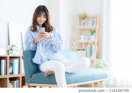 Young woman sitting and relaxing in living room Young woman sitting and relaxing in living room 118106790